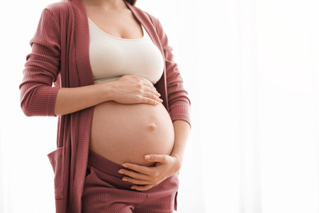 Unrecognizable Pregnant Lady Touching Her Naked Belly, Closeup Shot. Expectant Mother Standing...