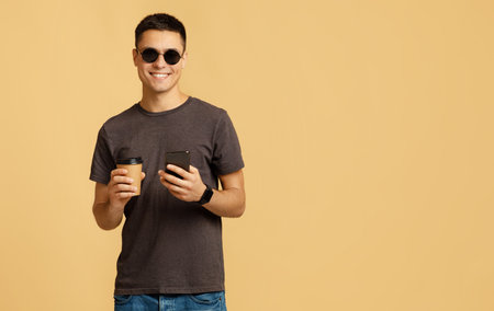 Stylish male model on break with gadget. Cheerful millennial handsome man student in sunglasses...