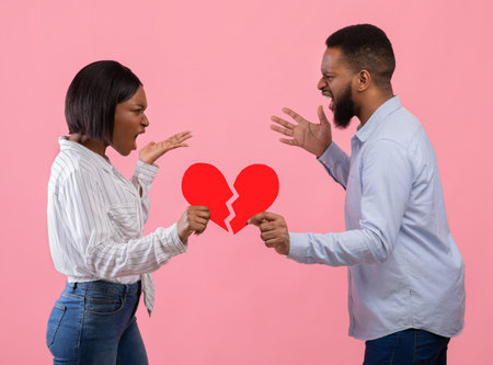 Angry young guy and lady with red heart cut in half shouting at each other, having conflict or fight...