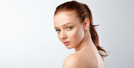 Female Beauty Portrait. Sensual Ginger-Haired Woman With Ponytail Hairstyle Posing Shirtless Looking At Camera On White Studio Background. Panorama With Free Space For Textの写真素材