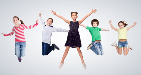 Cheerful Boys And Girls Jumping In Mid-Air Posing On Gray Studio Background. Positive Kids Jump In A Row Having Fun Together. Carefree Childhood Concept. Panorama, Collageの写真素材