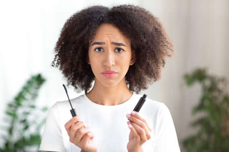 Problems with cosmetics, makeup, allergy and negative facial expressions. Sad young cute african...