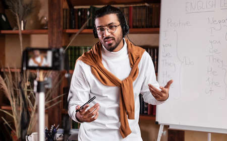 Indian Teacher Guy Filming Educational Video Lecture For Online Blog Standing Near Blackboard...