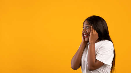 Side view of amazed african american woman with beautiful hair looking at empty space, touching her...