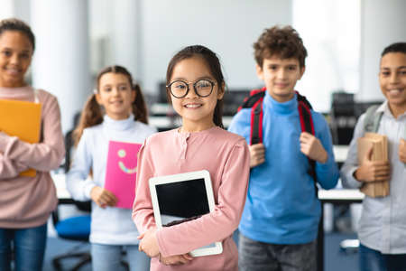 Pupils, Technology And Learning Concept. Smiling asian girl in eyeglasses holding digital tablet and...