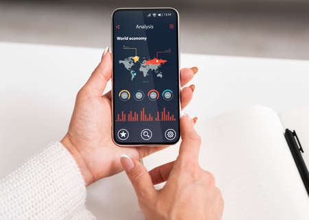 Business Analytics App With World Economy Data Charts And Graphs On Smartphone Screen In Female...