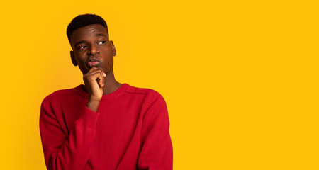 Pensive African American Guy Looking Aside At Copy Space And Touching Chin, Thinking About...