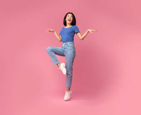 Full length of charming glad carefree delightful asian lady having fun, being in a good mood, jumping at studio and looking at copy space isolated over bright pink background wallの写真素材