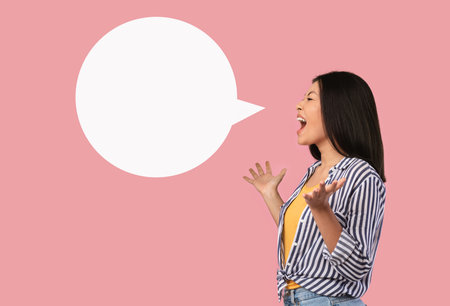 Portrait of emotional asian woman screaming at blank speech bubble. Free place for your text, lady...