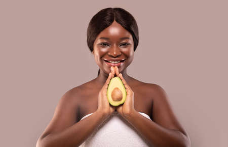 Natural Skincare. Portrait of young beautiful african american woman holding ripe fresh avocado...
