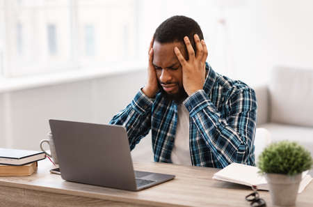 Stressed Black Businessman Having Headache Sitting At Laptop Having Problem At Workplace In Modern...
