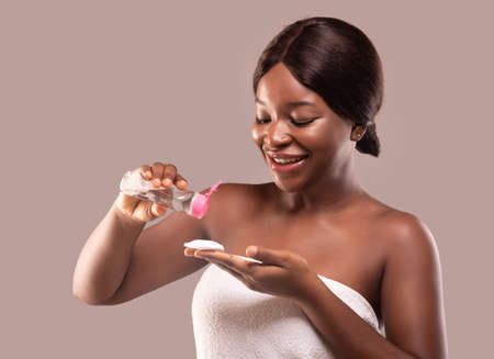 Face Cleansing Concept. Attractive Black Lady Pouring Micellar Water On Cotton Pad, Ready To Remove...