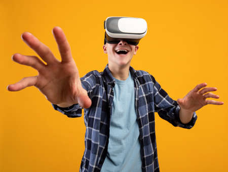 Portrait of excited young guy experiencing virtual reality in VR headset, moving hands, making...