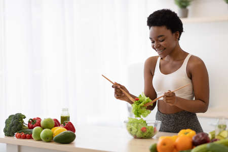 Weight Loss Nutrition. Side View Of Black Skinny Lady Cooking Vegetable Salad Standing In Modern...
