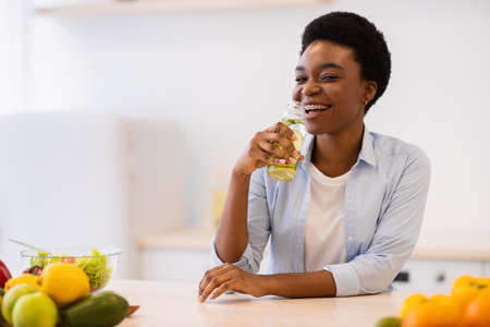 Healthy Hydration. Cheerful Black Lady Drinking Infused Water For Refreshment Posing With Bottle...
