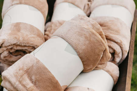 Accessories and textiles for modern wedding inside or for hotel, cafe or restaurant. Packed soft beige blankets for guests for outdoor banquet or party, top view, flat lay, close up, free spaceの写真素材