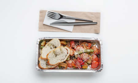 Healthy food, home cooking from restaurant, delivery lunch to work. Container with tasty fresh salad with slices of bread, plastic cutlery, isolated on white background, top view, panorama, copy spaceの写真素材