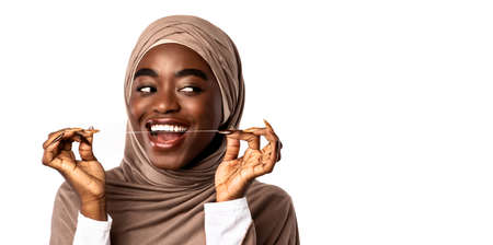 Oral Hygiene And Health Care. Portrait of smiling confident muslim black woman using dental floss,...