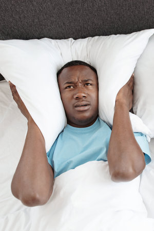 Snoring, insomnia, bad sleep, loud neighbors. Upset tired young african american man freaking out