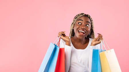 Special Big Holiday Sales Concept. Excited young black woman with braids holding colorful shopping...
