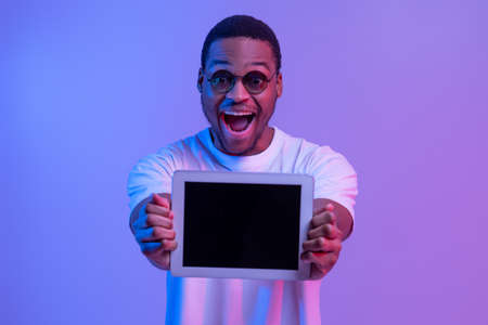 Excited African American Guy Showing Digitral Tablet With Black Screen At Camera, Demonstrating Free...