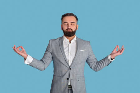 Workplace stress management concept. Peaceful office employee meditating with closed eyes on blue...