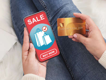 Female hands holding smartphone and credit card, shopping online