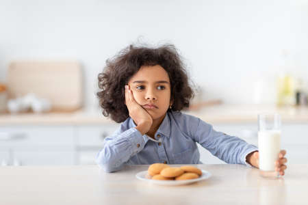 Portrait Of Sad Little Afro Girl Holding Glass Of Milkの写真素材