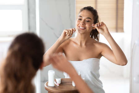 Young Lady Flossing Cleaning Teeth With Tooth Floss In Bathroomの写真素材