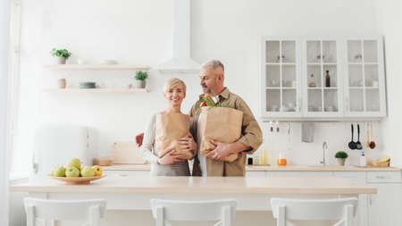 Eco friendly shopping, senior couple unpacking bag with organic food from supermarketの写真素材
