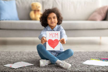 Smiling afro girl showing greeting card for mothers dayの写真素材
