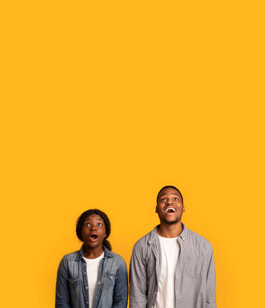Portrait of amazed black man and woman looking up with opened mouthの写真素材