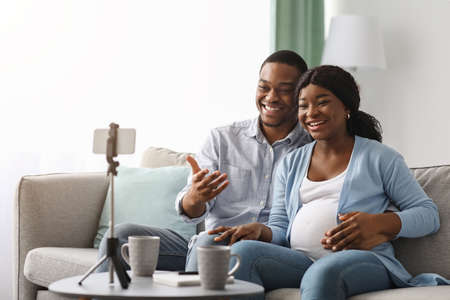 Cheerful black bloggers broadcasting from home, pregnancy blog conceptの写真素材