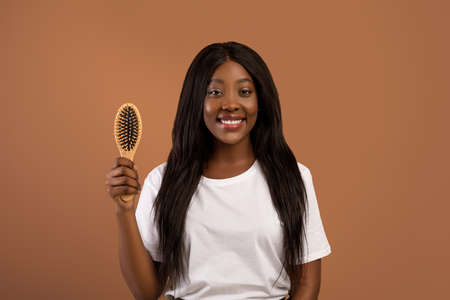 Attractive black woman holding wooden hair brushの写真素材