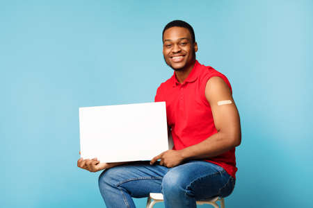 Vaccinated Black Guy Showing Blank Poster Sitting Over Blue Backgroundの写真素材