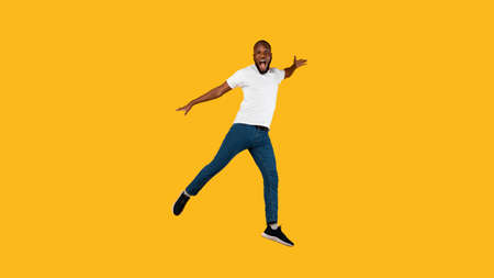 African Guy Jumping Shouting Looking At Camera, Yellow Background, Full-Length