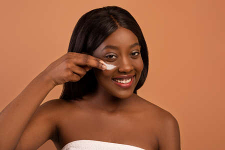 Delighted african american pretty naked lady with eye creamの写真素材