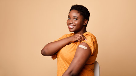 Black Woman Showing Vaccinated Arm After Vaccine Injection, Beige Backgroundの写真素材