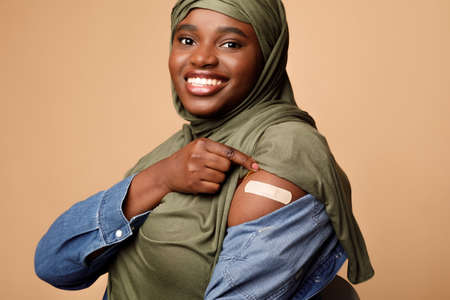 Muslim Lady Showing Vaccinated Arm After Vaccine Injection, Beige Backgroundの写真素材