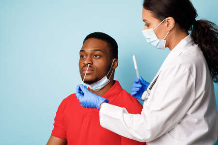 Doctor Making Covid-19 PCR Test For Male Patient, Blue Background