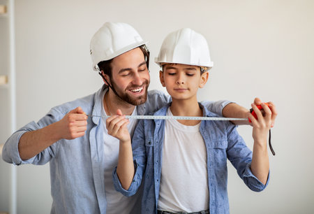 Happy dad and his son making measurements using roulette, dad teaching boy for construction workingの写真素材
