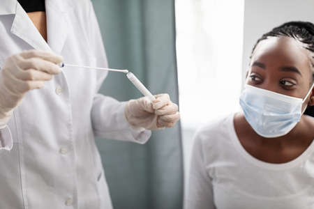 Doctor taking PCR test sample from potentially infected afro lady