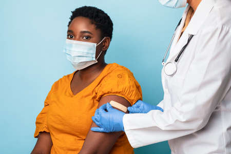 Nurse Applying Plaster Strip On Vaccinated Patients Arm, Blue Background