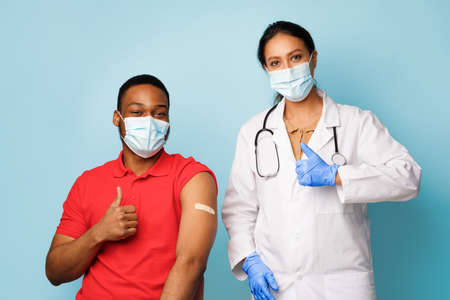 Vaccinated African Man And Nurse Gesturing Thumbs-Up Over Blue Background