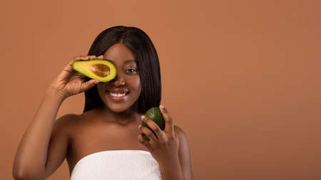 Beautiful black lady with halves of avocado