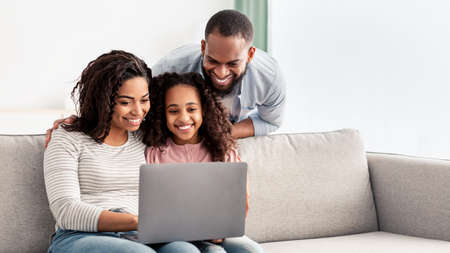 Happy african american family using laptop in living roomの写真素材