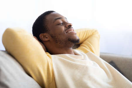 Closeup of black guy relaxing on couch at homeの写真素材
