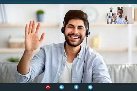 Remote distant communication. Arab man in headphones having video online conference with colleague, monitor screenshotの写真素材