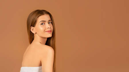 Portrait of beautiful young lady with straight silky hair posing on brown background, banner design...