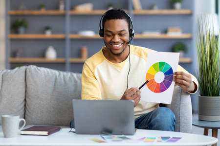 Happy black guy art-manager having video conference from homeの写真素材